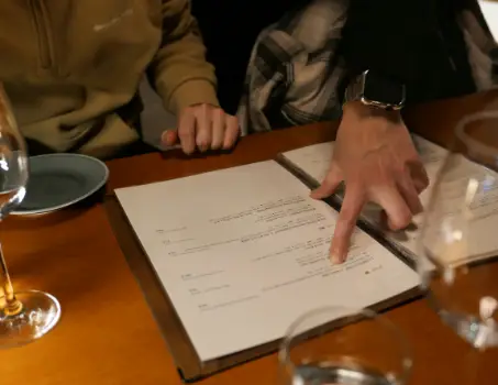 Imagen de una carta de restaurante y 2 personas indicando su selección